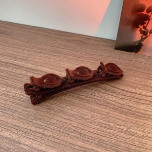 Detail of dark brown flocked hair clip featuring three decorative 3D rose ornaments