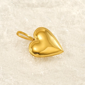 Polished heart shaped stainless steel gold pendant displayed on a soft textured background