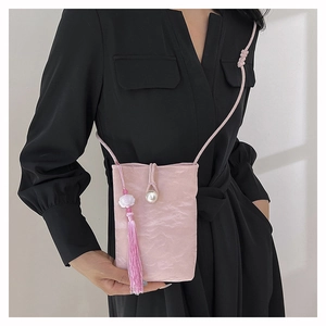 Détail du mini sac bandoulière rose avec boucle perle, pompon et texture froissée