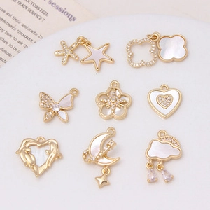 Detail view of 8 gold plated charms with natural white shell inlays and zircon accents