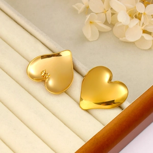 Close-up of golden heart earrings in a jewelry box showing the secure post and back closure