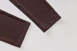 Detailed close-up showing durable double-needle stitching on dark brown knit yoga jumpsuit