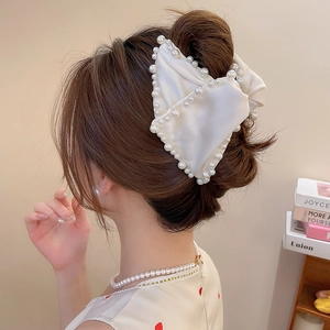 Détail d'une pince à cheveux élégante en satin blanc avec perles sur le modèle