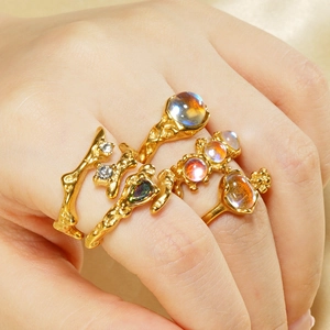 Detailed view of stacked gold moonstone rings with textured irregular metal design