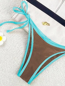 Detail of brown and blue bikini bottom with side ties and a gold shell hardware