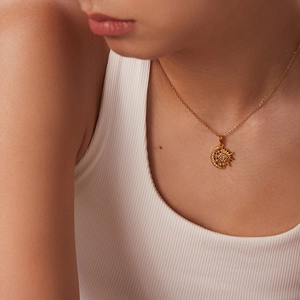 Close-up of a 18k gold plated sun and moon pendant necklace with cubic zirconia on a model