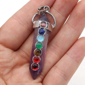 Détail d'un pendentif améthyste hexagonal avec sept pierres de chakra colorées