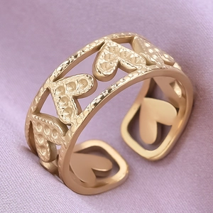 Macro shot of gold heart ring with hammered texture on soft purple satin fabric