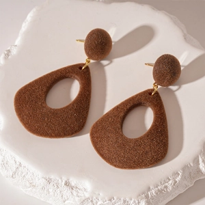Vue macro de boucles d'oreilles gouttes floquées marron sur fond de pierre blanche