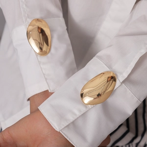 Elegant gold oval sunburst cufflinks set displayed on a white dress shirt sleeve