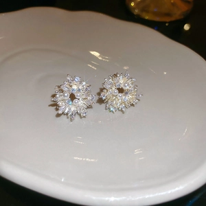 Macro detail of starburst pearl earrings with glittering cubic zirconia on a ceramic tray