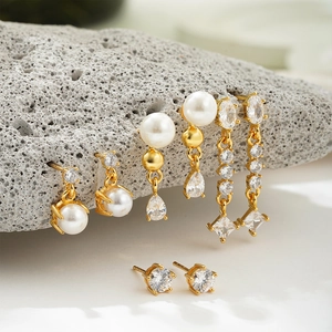 Detail of 18K gold earrings set featuring white pearls and clear zircon on grey stones