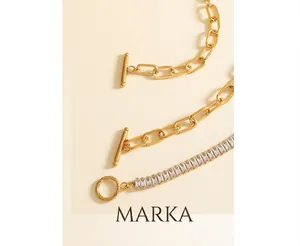 Detail of gold paperclip and zircon tennis chains with OT toggle clasp on wooden base