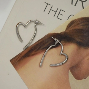 Detailed close-up of S925 sterling silver heart-shaped stud earrings on magazine page