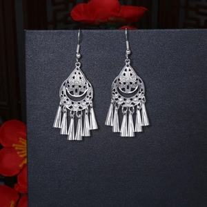 Detailed macro view of silver flower fan earrings with long cone tassels on black background