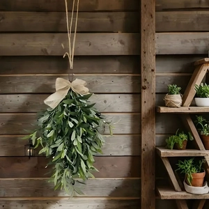 Artificial olive leaf door swag with dark fruit and beige bow on a rustic wooden wall