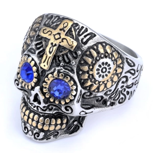 Detail of vintage skull ring with gold cross and blue stone eyes in stainless steel