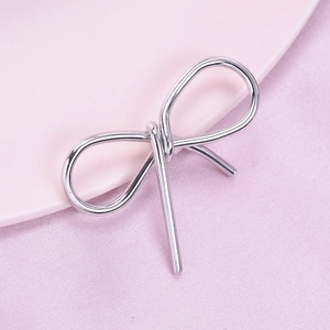 Détail du pendentif nœud en argent en acier inoxydable sur fond de tissu rose doux