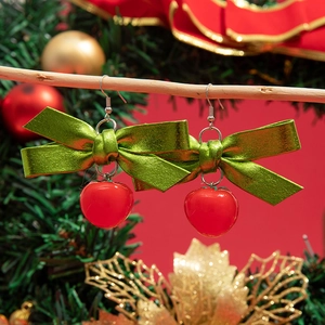 Gros plan de boucles d'oreilles de Noël avec nœud vert et breloque rouge sur branche