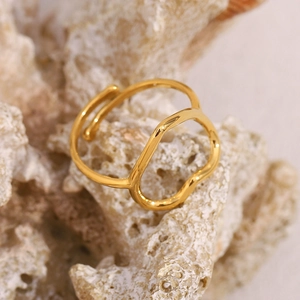 Detail of 18K gold-plated irregular wavy ring on cream-colored textured stone surface