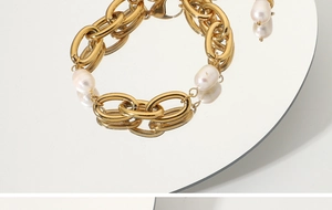 Détail de la gourmette en acier doré 18K avec perles blanches posée sur un miroir