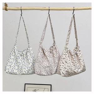 Floral canvas shoulder bags in blue, red, and black hanging on a wooden rail