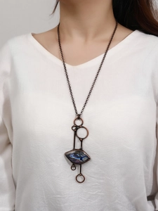 Close-up of vintage bronze labradorite pendant necklace worn on white linen apparel