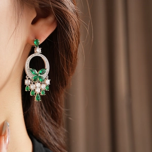 Gros plan d'un mannequin portant des boucles d'oreilles en argent et pendentifs émeraude