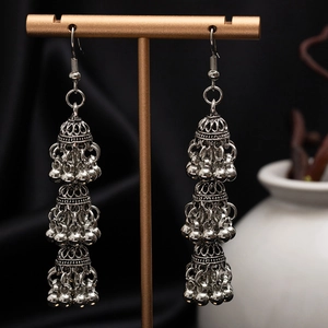 Detailed shot of silver triple-tier Jhumka earrings with ornate floral carving