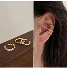 Detailed view of three gold ear cuffs including smooth, twisted, and pave designs on model