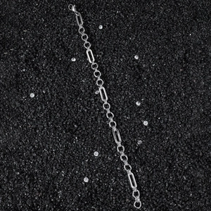 Close-up of silver stainless steel paperclip chain with oval links on black stone
