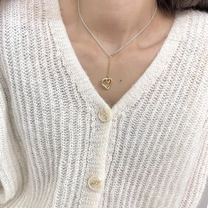 Macro detail of the adjustable S925 silver heart necklace on a model wearing white knitwear