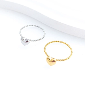 Detailed view of silver and gold twisted rope rings with polished heart charms
