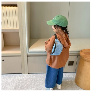 Rear view of a child wearing a denim crossbody chest bag in a modern indoor setting