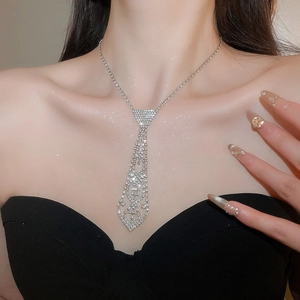 Close-up of sparkling rhinestone tie-shaped necklace with pearls on a model