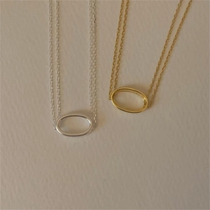 Detail of minimalist gold and silver oval pendant necklaces on textured background