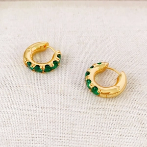 Chic gold hoop earrings inlaid with vibrant green cubic zirconia on textured fabric