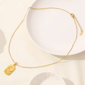 Detailed close-up of a gold celestial rectangular pendant with crescent moon and sunburst rays