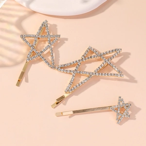 Golden five-pointed star hair clips with sparkling rhinestones set on beige background