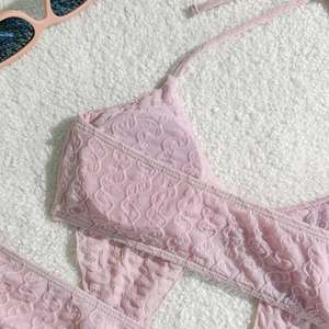 Detailaufnahme des rosa Bikini-Tops mit strukturierter Textur auf weißem Plüschgrund