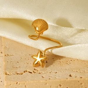 Detailed close-up of 18K gold starfish and seashell ear cuff on beige silk and stone