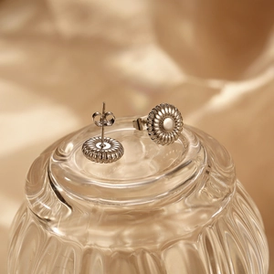 Elegant silver petal earrings with radial stripes on a reflective gold silk backdrop
