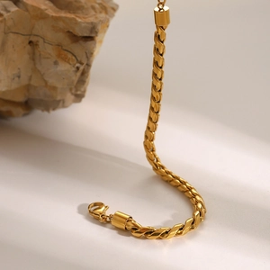 Detailed view of the twisted gold chain necklace resting elegantly on a natural stone base