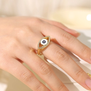 Close-up of golden evil eye ring with blue stones on a finger in soft lighting