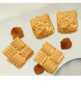 Details von goldenen Vintage-Ohrsteckern mit Textur und Blumenform auf Spiegeloberfläche