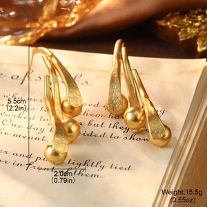 Detailed close-up of golden branch drop earrings with floral texture on vintage paper