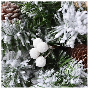 Macro shot of snow-flocked pine needles with natural pine cones and white berries