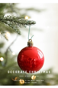 Close-up of a red festive ornament hanging on a pine branch with a green metal hook