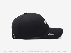 Side view of a black cotton baseball cap showing detailed embroidery and a metal ring buckle