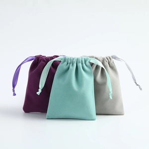 Velvet drawstring jewelry pouches in purple, mint green and grey on white background